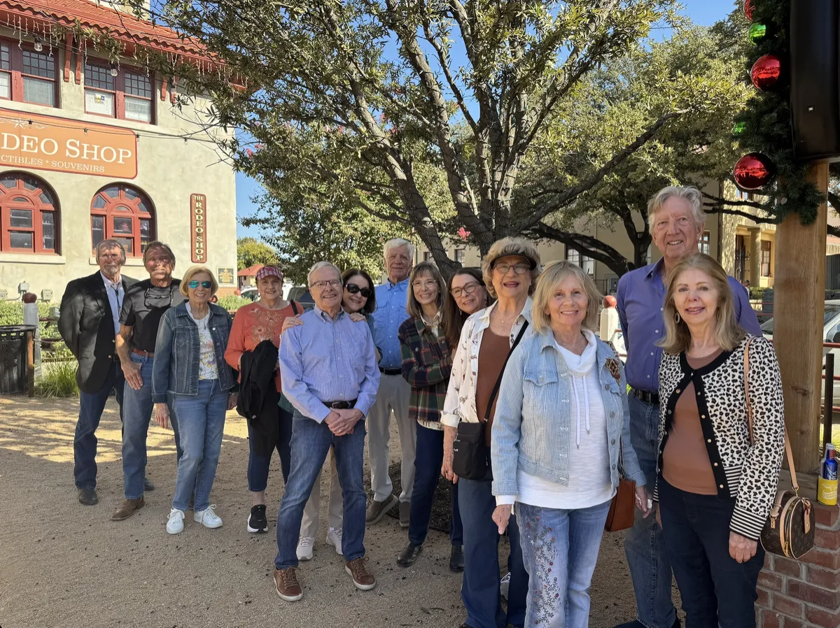 A group of about a dozen guests posing under a tree outside the Rodeo Shop in the Stockyards